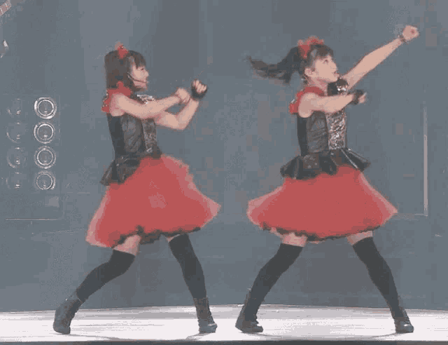 two girls in red dresses are dancing on stage