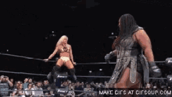 a woman in a corset is standing in a boxing ring with a crowd watching .