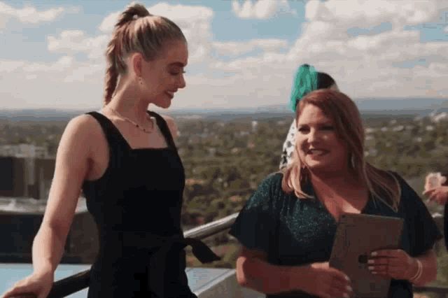 a woman in a black dress stands next to another woman