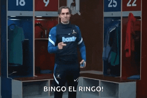 a man in a blue shirt is standing in a locker room holding a can of beer .