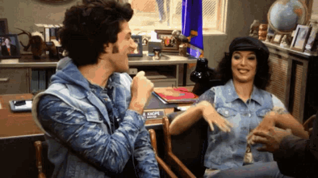 a man and a woman are sitting in front of a desk that says e shops