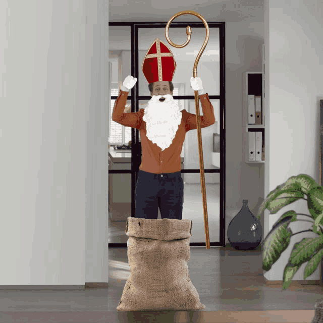 a man dressed as st nicholas is holding a cane and a bag of presents