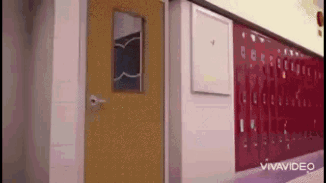 a hallway with red lockers and a yellow door in a school .