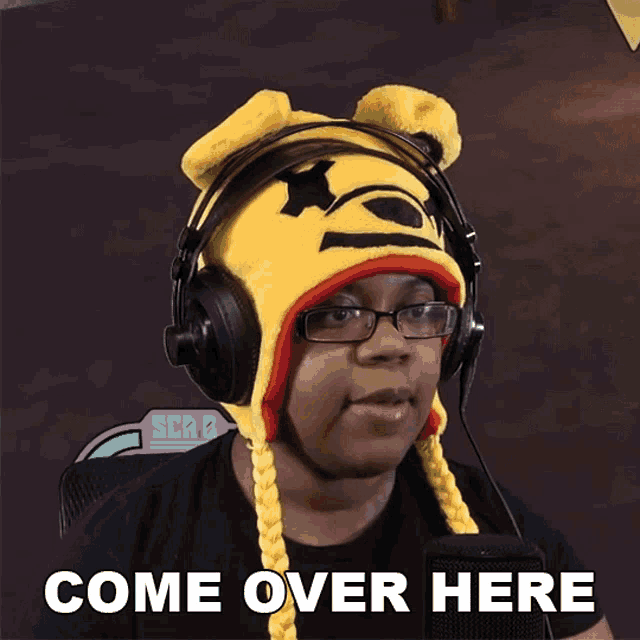 a woman wearing headphones and a yellow hat with the words come over here below her