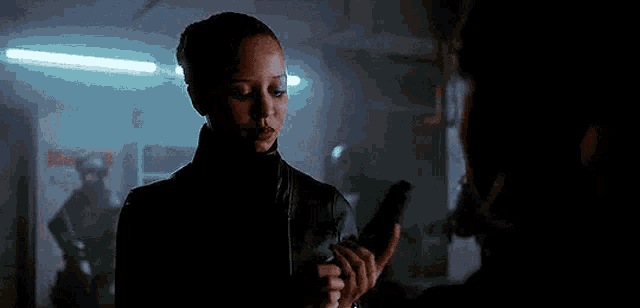 a woman is holding a gun in her hand and talking to a man .
