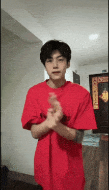 a young man in a red shirt is clapping his hands in a room