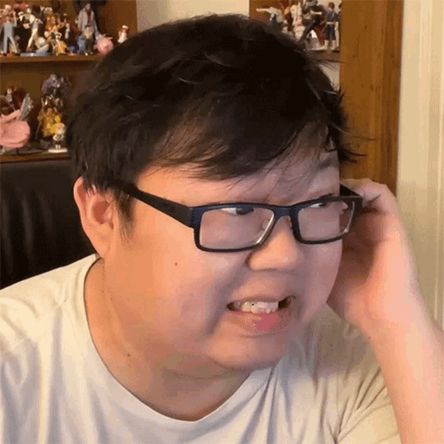 a man wearing glasses is making a funny face in front of a shelf full of figurines