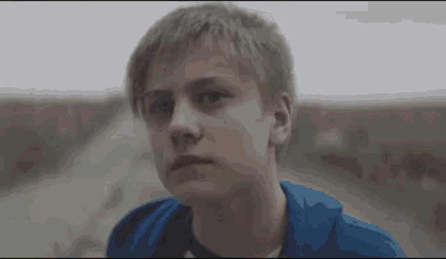 a boy in a blue shirt looks at the camera