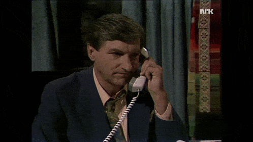 a man in a suit is talking on a phone with the letters nrk visible