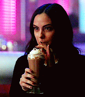 a woman is drinking a milkshake with whipped cream
