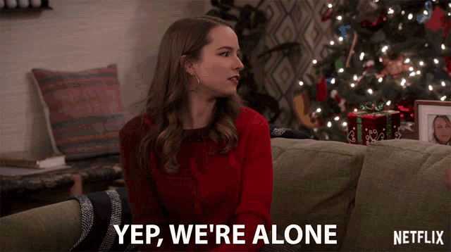 a woman in a red sweater sits on a couch with a netflix logo in the corner