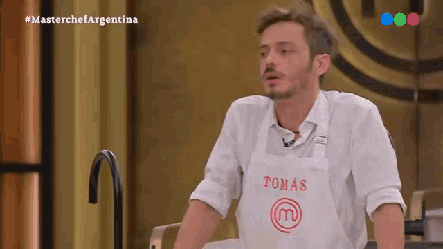 a man wearing a white shirt and an apron with tomas on it