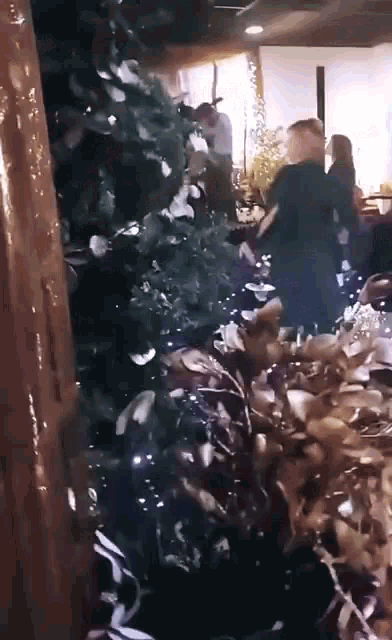 a group of people are standing in front of a christmas tree .
