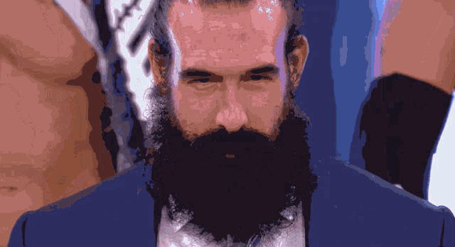 a man with a beard is wearing a blue suit and white shirt