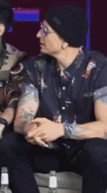 a man wearing sunglasses and a black beanie is sitting on a couch