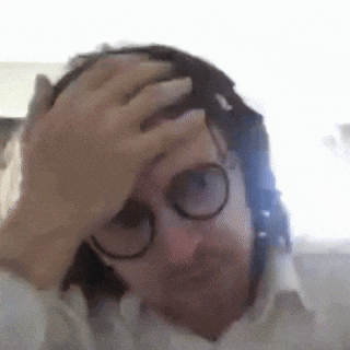 a man wearing glasses and a white shirt is holding his head .
