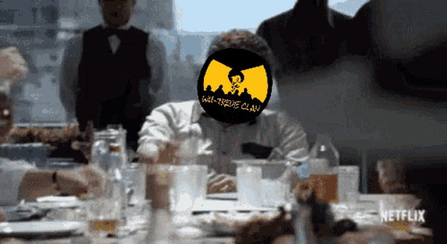 a man sits at a table with a sticker on his face that says wall-to-the-pe-clan