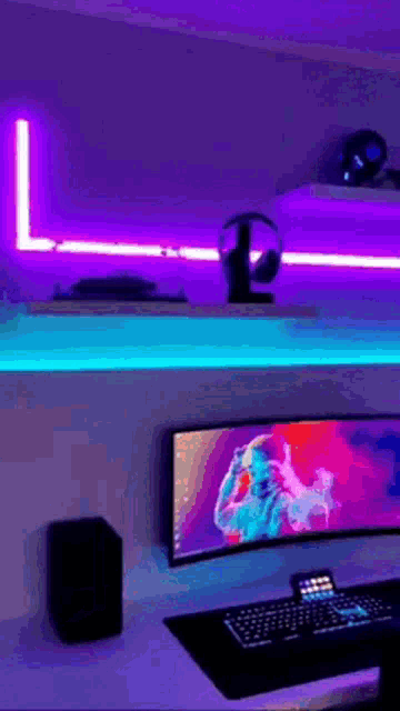 a computer is sitting on a desk in a room with purple lights behind it .