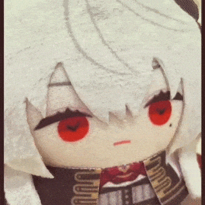 a stuffed doll with white hair and red eyes is sitting on a table .