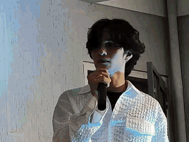 a man in a white shirt holds a microphone to his mouth