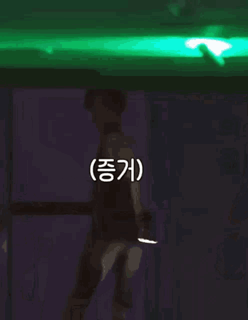 a person in a dark room with a green light behind them
