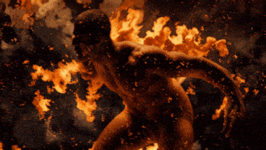 a man is surrounded by flames and smoke in a dark room