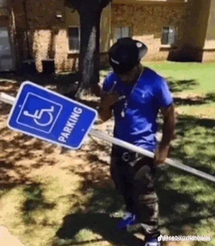 a man is holding a handicapped parking sign .