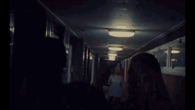 a group of people standing in a dark hallway talking to each other .