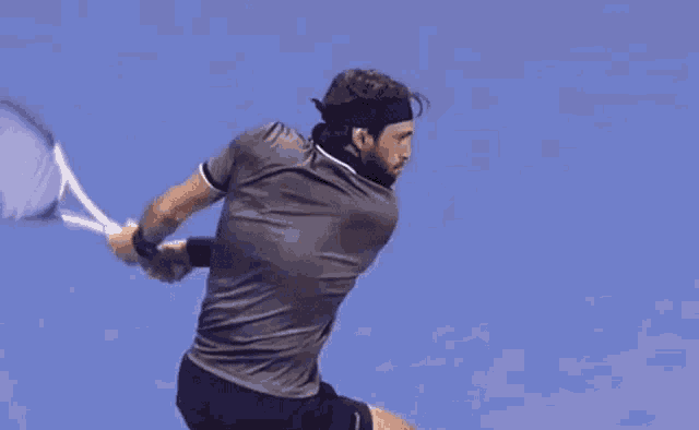 a man is swinging a tennis racquet with the letter m on his wrist