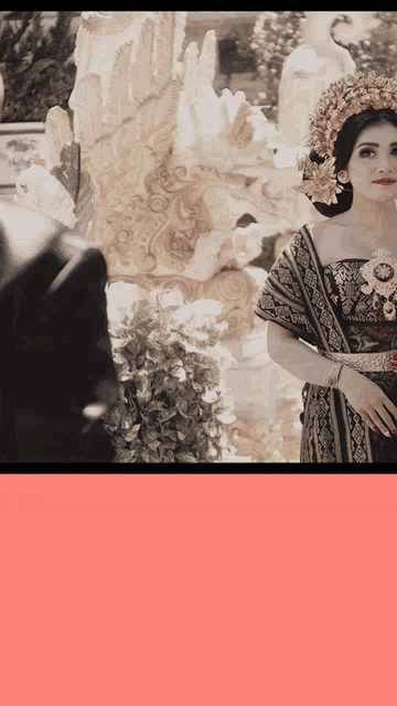a woman in a black and gold dress stands in front of a man in a suit