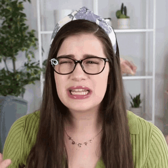 a woman wearing glasses and a headband making a funny face .