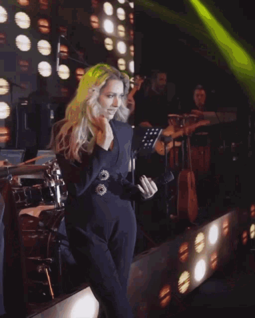 a woman in a blue jacket is dancing on stage
