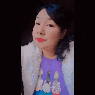 a woman wearing a purple shirt and a white jacket is making a funny face