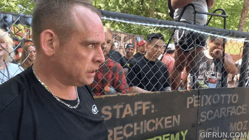 a man stands in front of a sign that says " staff rechicken "