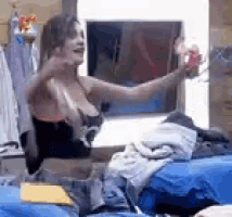 a woman is sitting on a bed taking a picture of herself in a mirror .