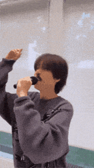 a person singing into a microphone with their arms in the air
