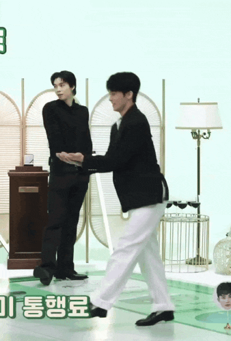 two men are standing next to each other in a room with korean writing on the bottom