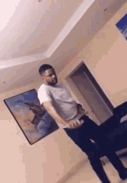 a man is dancing in a living room with a picture on the wall .