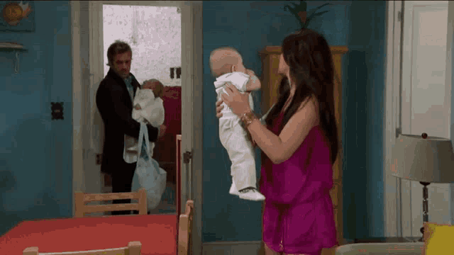 a woman in a pink dress is holding a baby while a man in a suit holds another baby