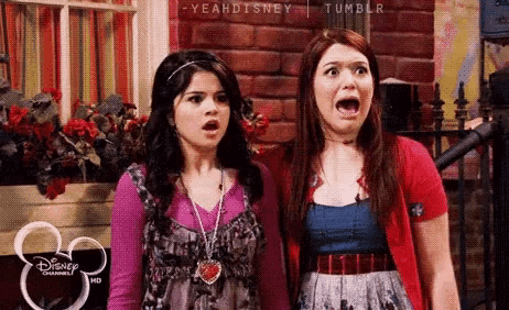 two girls are standing next to each other with their mouths open and their faces surprised .