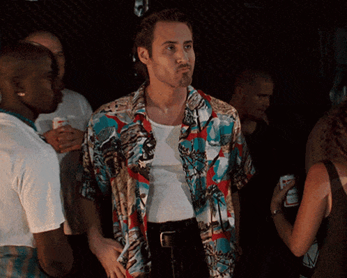 a man in a hawaiian shirt stands in a crowd of people