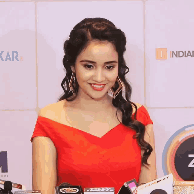 a woman in a red dress stands in front of a wall that says " kar "
