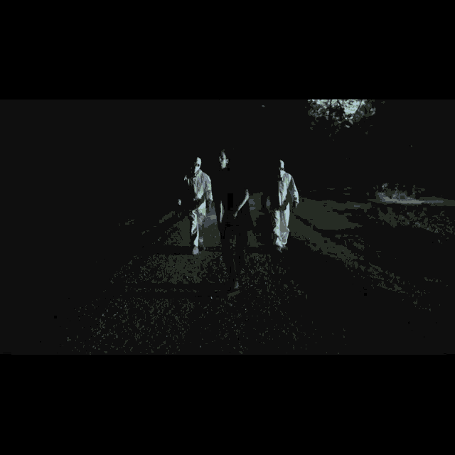 a group of people wearing gas masks are walking down a road at night