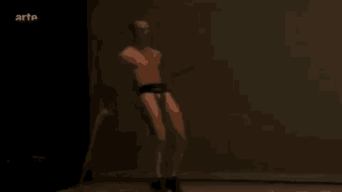 a man without a shirt is jumping a jump rope while holding a pair of crutches .
