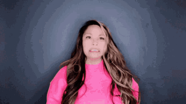 a woman with long hair is wearing a pink shirt