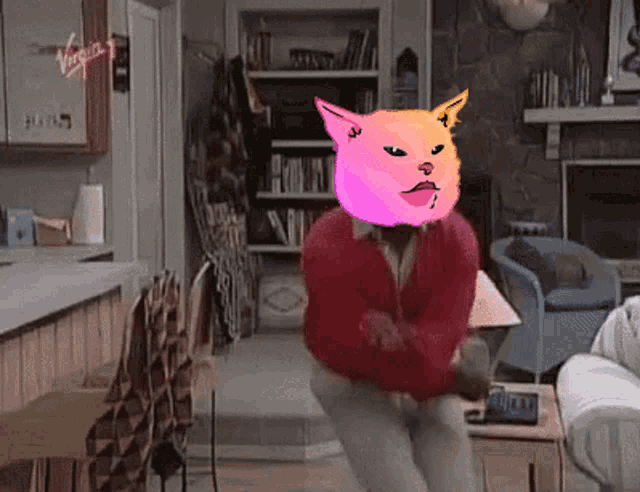 a man is dancing in a living room with a pink cat head