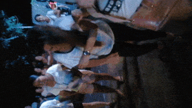 a group of people are standing in a dark room and one of them is wearing a shirt that says ' a '