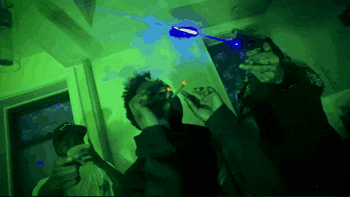 a man smoking a cigarette in a room with a green light behind him