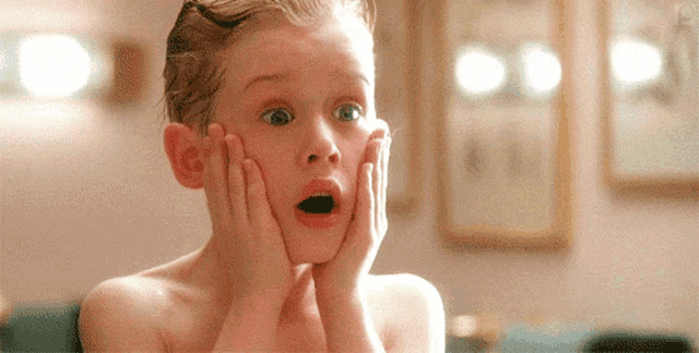 a young boy without a shirt is making a surprised face