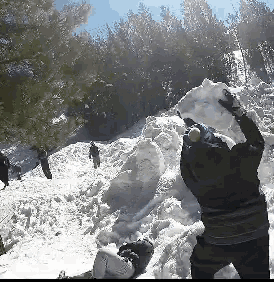 a person is standing in the snow holding a large snowball